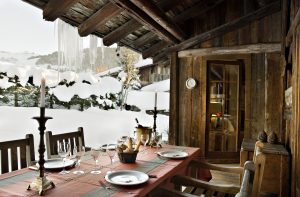 Dining area outside overlooking mountains at luxury French ski hotel.